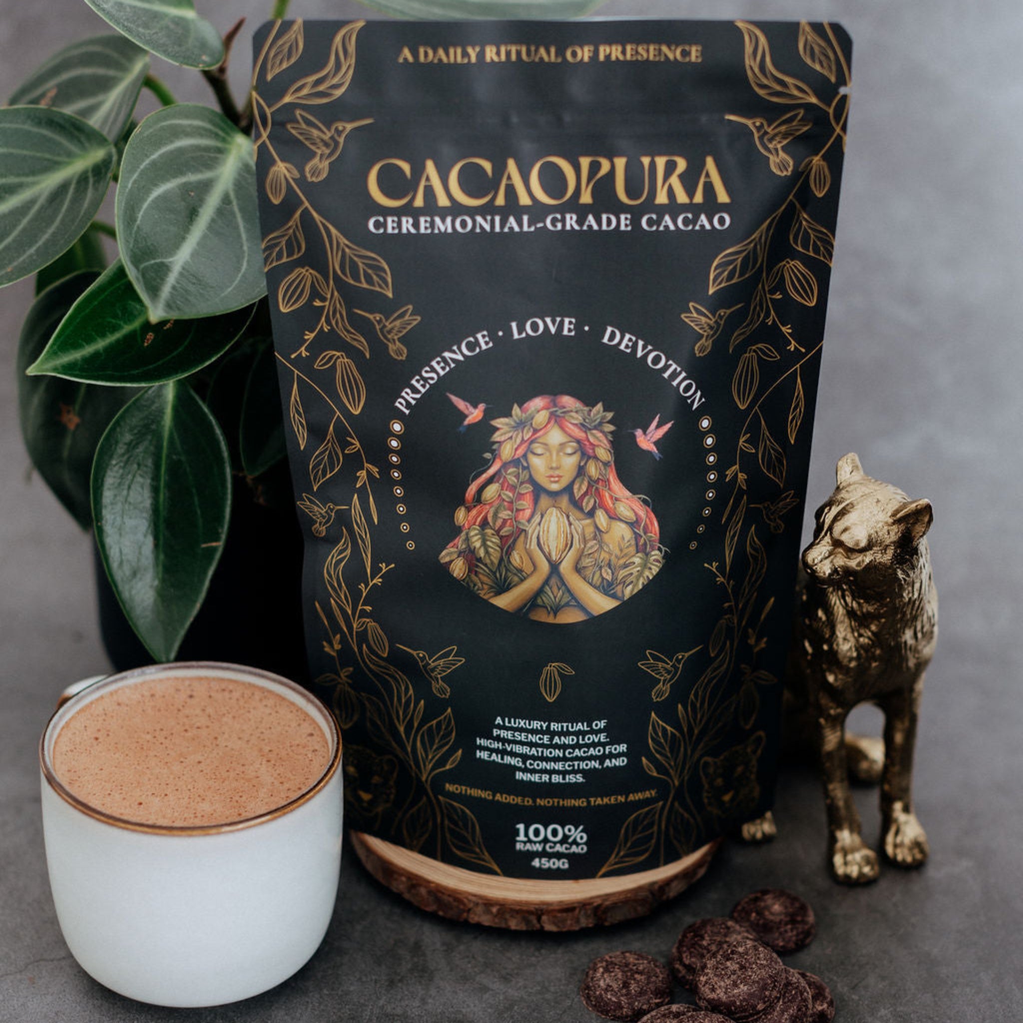 Cacaopura ceremonial-grade cacao packaging with a cup of cacao and chocolate truffles on a gray background.